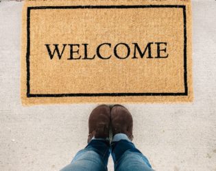 person in blue denim jeans standing on brown and black welcome area rug